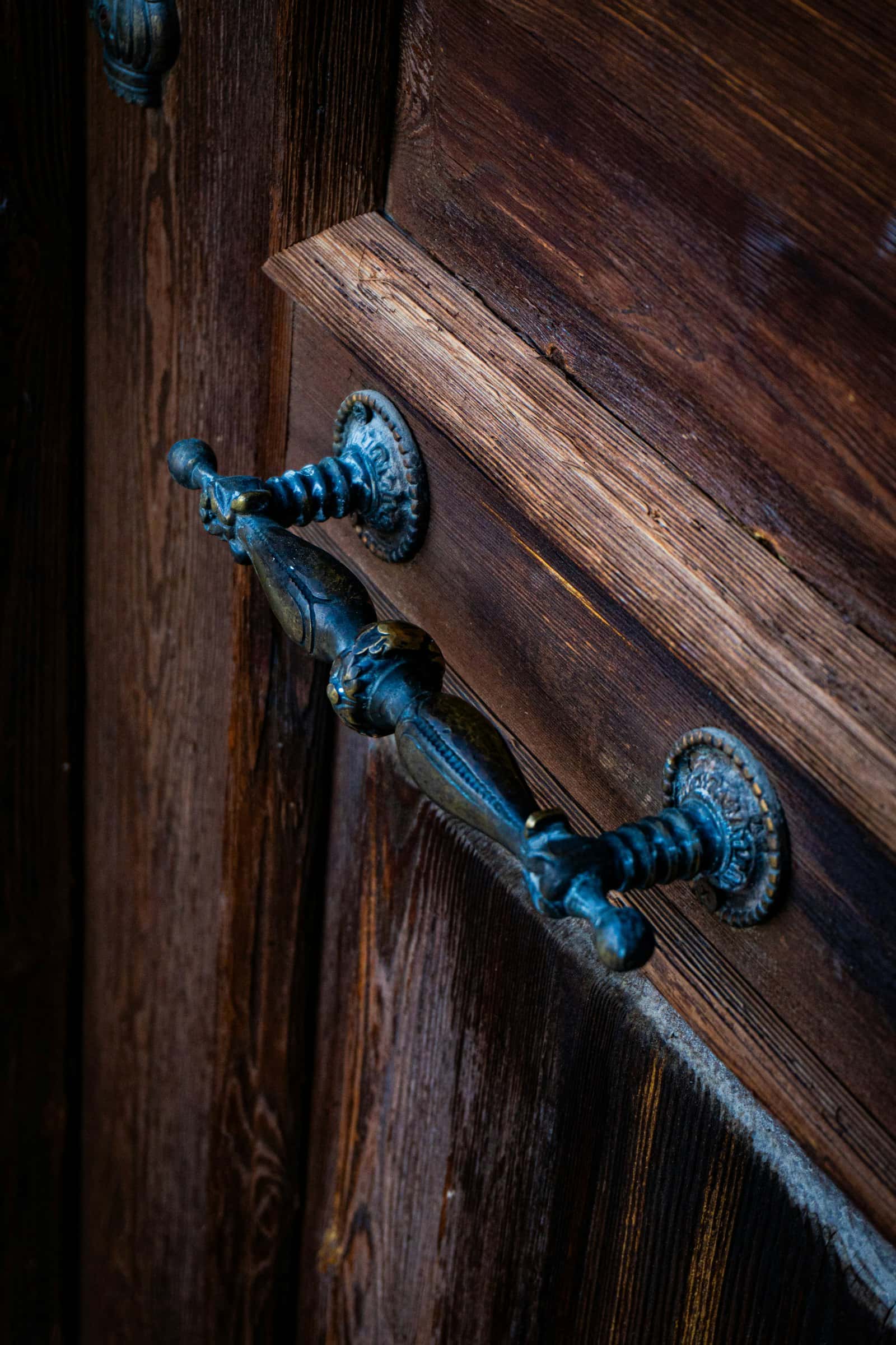 An old ornate door handle on weathered wood