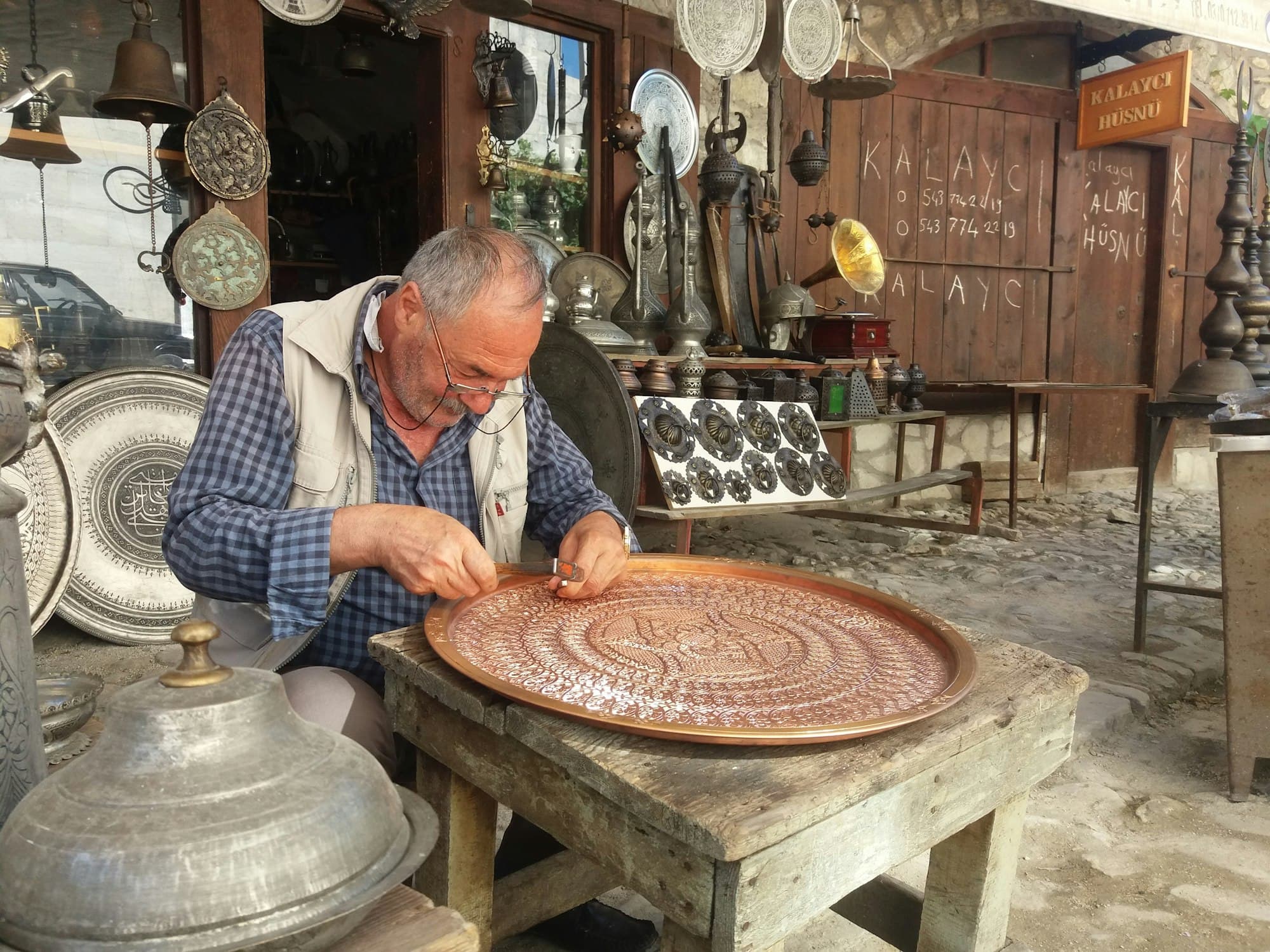 A craftsman chasing a pattern into a metal tray