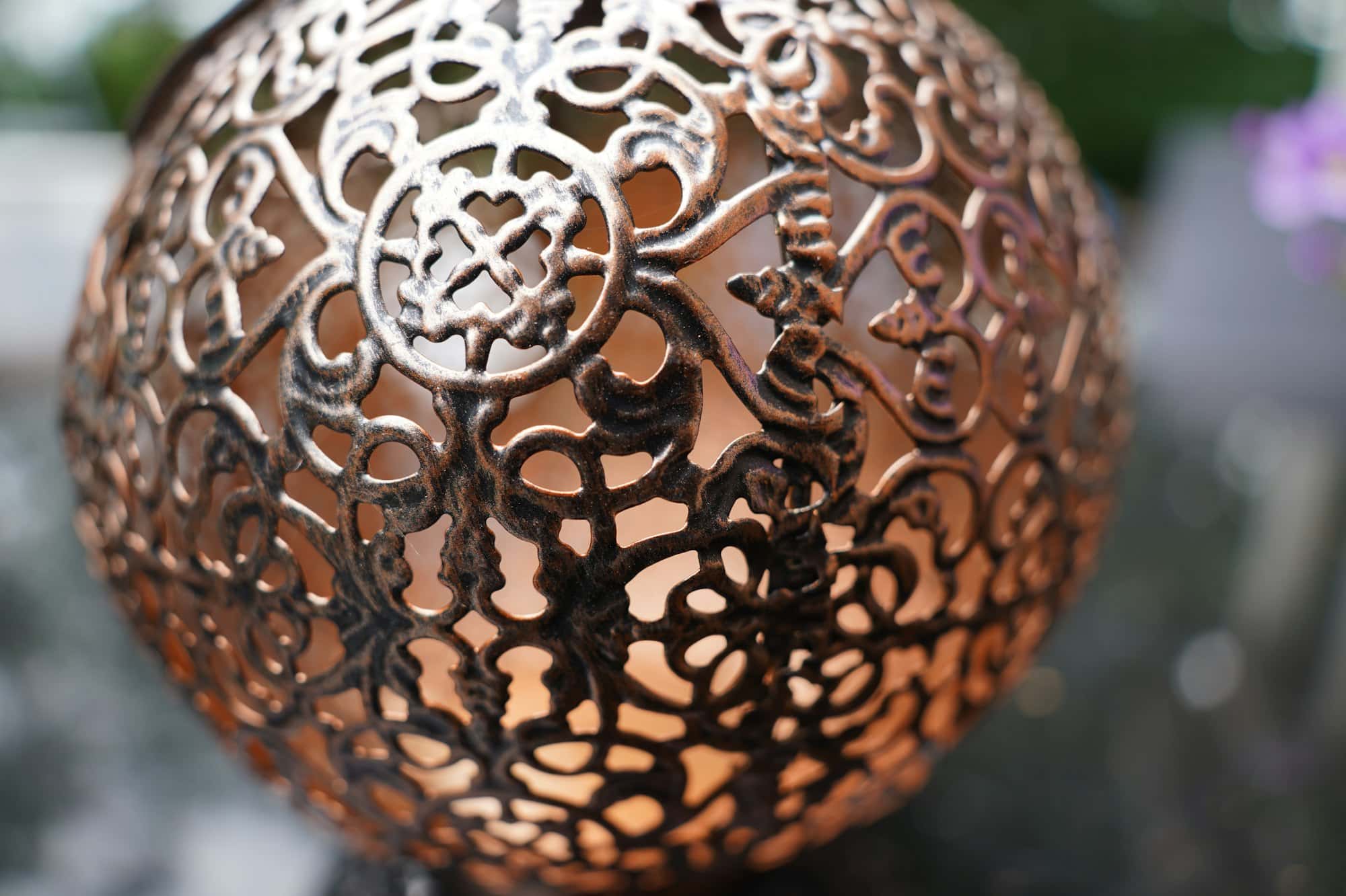 Close-up of a pierced metal lamp shade with light showing through the openings