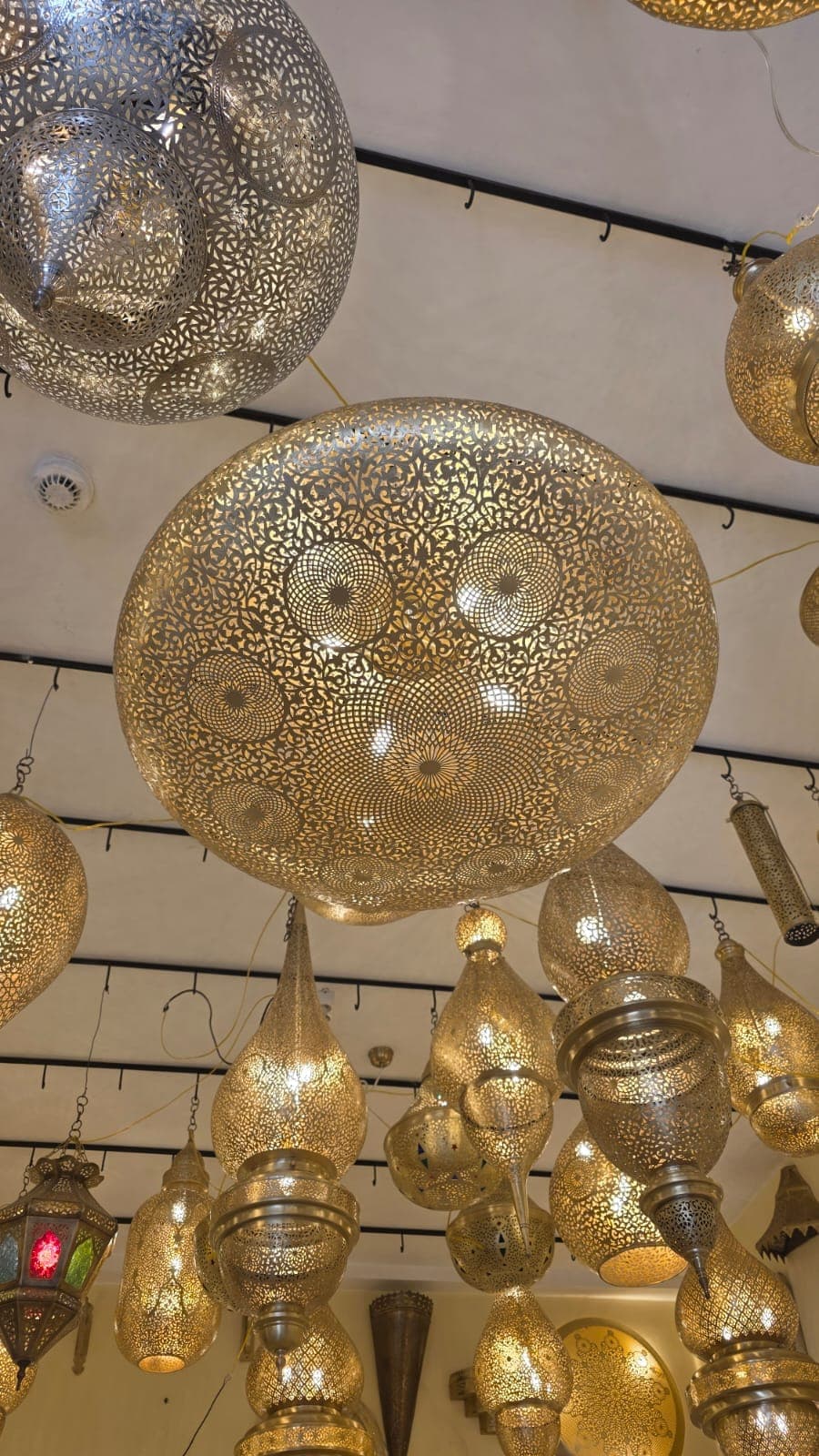 Round hand-pierced brass dome pendant, lit, among other lamps in the showroom