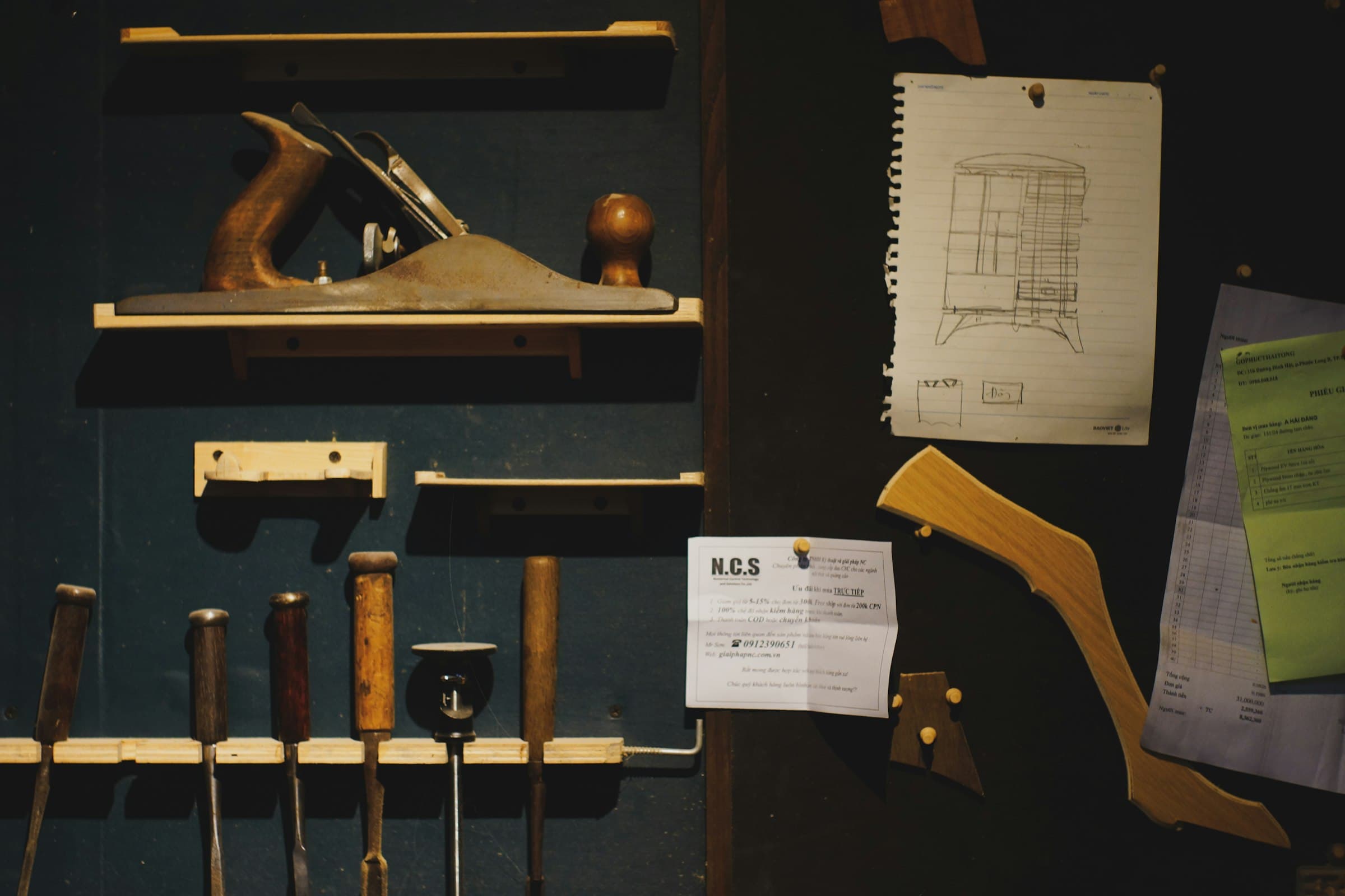 Tools and drawings pinned to a dark workshop wall