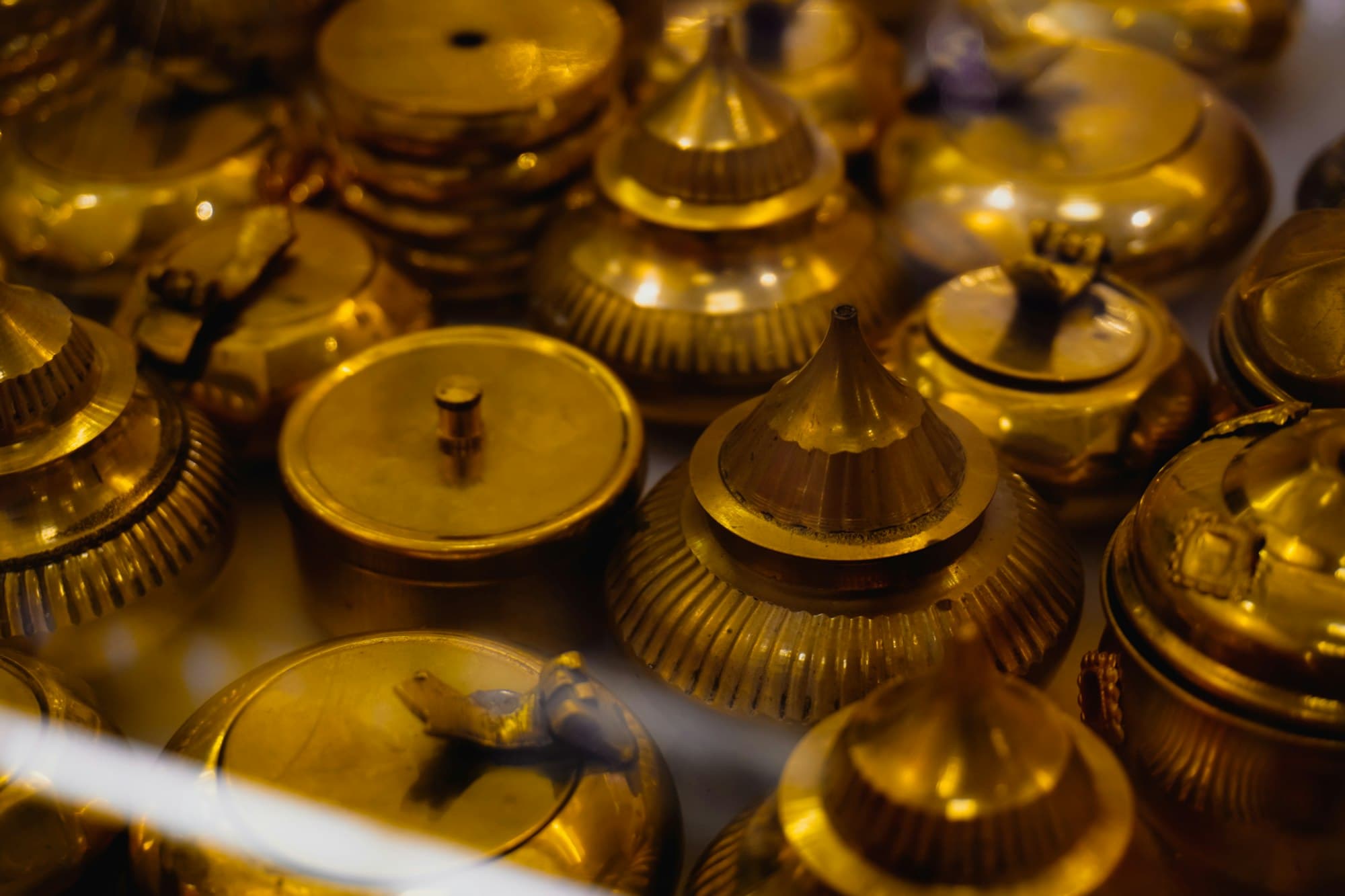 Polished brass lidded vessels crowded together on a shelf